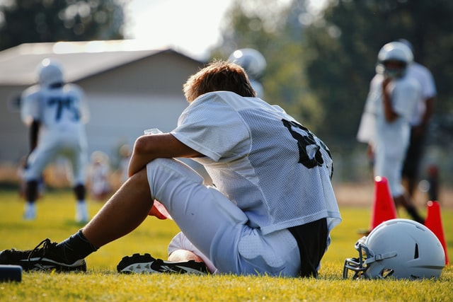 football player sitting on grass